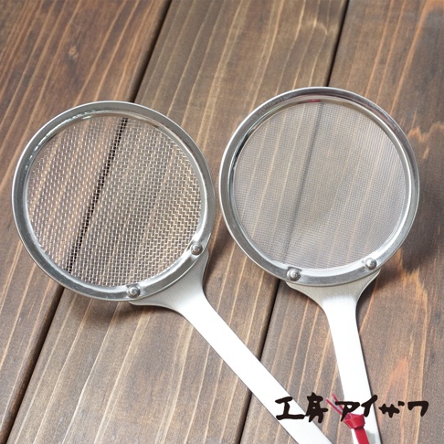兩個銀色不鏽鋼萬用撈泡勺，帶有細網篩網，放在木紋背景上。