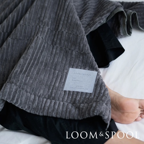 深灰色純棉立體直紋單人毯，觸感柔軟，帶有品牌標籤。