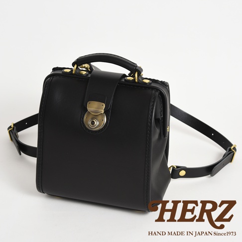 黑色皮革迷你後背醫生包，配有金色金屬旋鈕鎖扣、手提把及可調式肩帶。