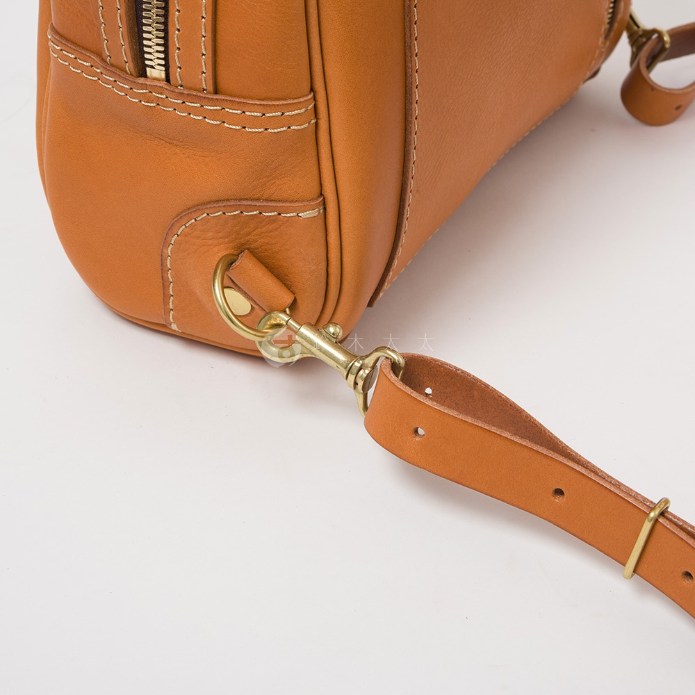 鞣革棕色皮革後背包，特寫金屬扣環與皮革背帶，展現職人手作細節。