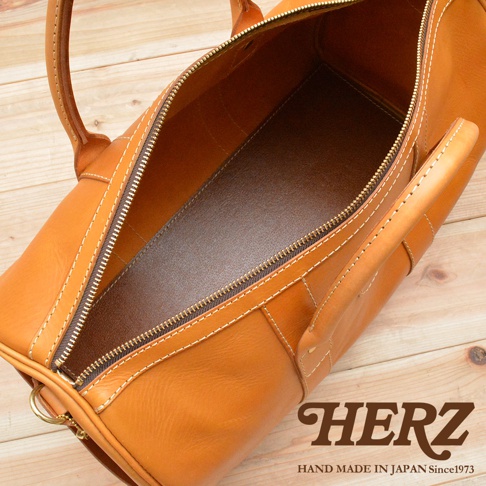 職人手作皮革波士頓包，採用天然棕色皮革，配有黃銅色拉鍊和縫線，展現簡約的設計與精緻的工藝。