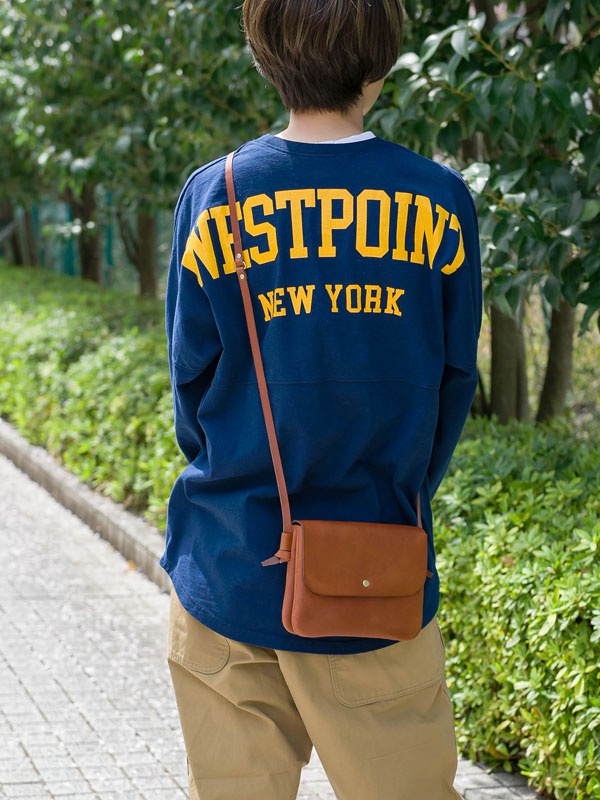 職人手作皮革直式隨行袋，棕褐色皮革材質，設有磁扣翻蓋和可調式斜背帶。