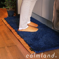 深藍色毛絨廚房地墊，帶有棕褐色邊緣，腳上穿著棕褐色拖鞋，踩在地墊上。