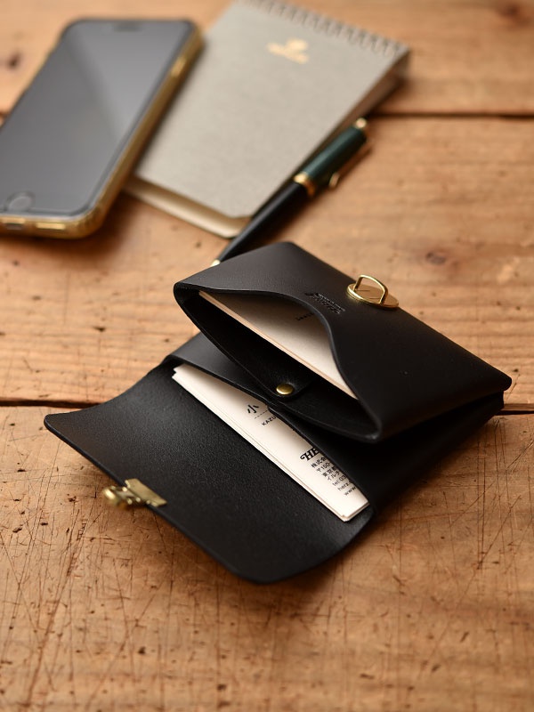 職人手作黑色皮革小卡片收納夾，附黃銅金屬扣，內有白色名片。