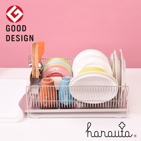 橫放式不鏽鋼碗碟架，包含多個碗盤、彩色杯子、餐具，以及附帶的瀝水盤，整體為銀色金屬材質，背景為粉紅色。