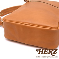 職人手作皮革長方型後背包，採用淺棕色皮革，設有拉鍊開口和可調式肩帶，展現簡約設計。