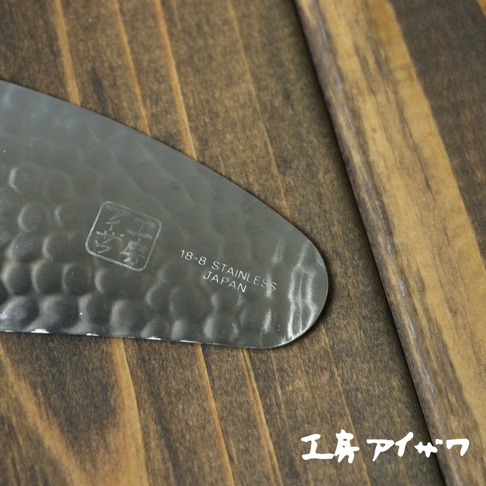 不鏽鋼茶勺，表面有槌紋，印有「18-8 STAINLESS JAPAN」字樣，置於木製背景上。