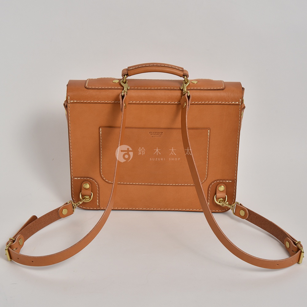 職人手作皮革傳統歐風三用學生包，呈現自然的棕褐色，搭配金屬扣環和縫線細節，展現復古質感。