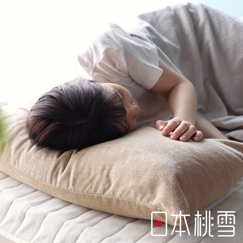 淺米色絲絨風毛巾枕套，質地柔軟，表面有細緻毛絨感，搭配一位側臥的亞洲女性，她正將臉埋在枕頭裡，頭髮散落在枕套上。