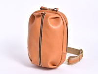 淺棕色皮革製成的立體運動斜背包，有明顯的縫線和金屬拉鍊。背包帶為米色織帶，搭配金色扣環。