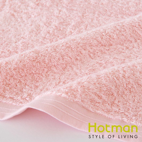 一條粉色柔軟的棉質浴巾，毛圈蓬鬆，邊緣有精緻的織紋。