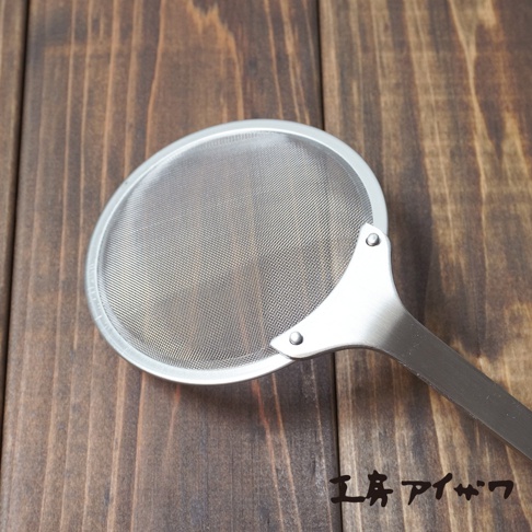 一個不鏽鋼萬用撈泡勺，帶有圓形細網篩和金屬手柄，置於木紋背景上。