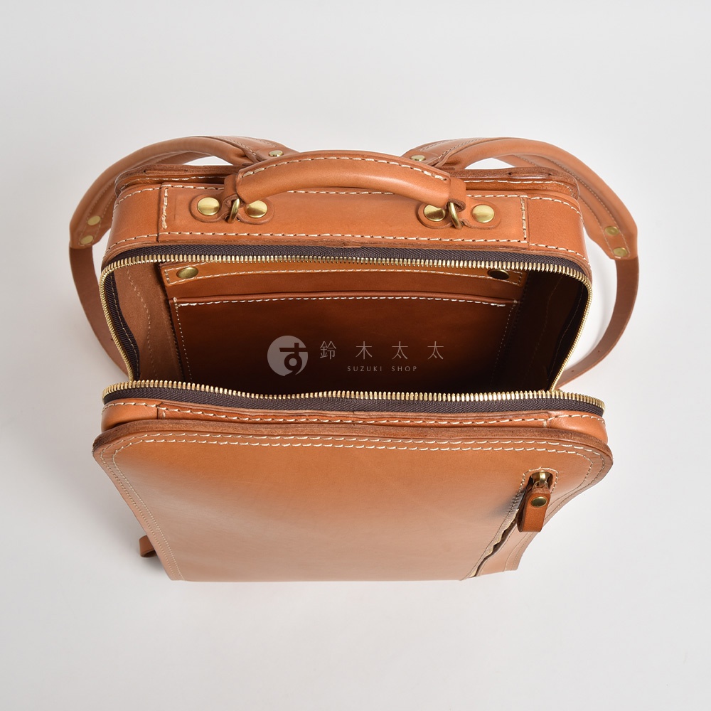 職人手作皮革商務電腦後背包 R-25，此款為棕褐色皮革，設計簡約，開口處可見內袋隔層，搭配金屬拉鍊與鉚釘，整體質感佳。
