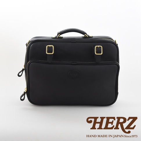 黑色皮革兩用商務公事包，配有金屬扣環、拉鍊和頂部提把，包身中央有品牌壓紋標誌。