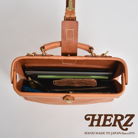 職人手作皮革迷你軟皮杜勒斯包，展示包內結構，包含筆記本、文件夾及拉鍊內袋，材質為淺棕色皮革。