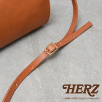 皮革手提包的肩帶，採用棕色皮革材質，配有金色方形調節扣，展現簡約的職人手作質感。