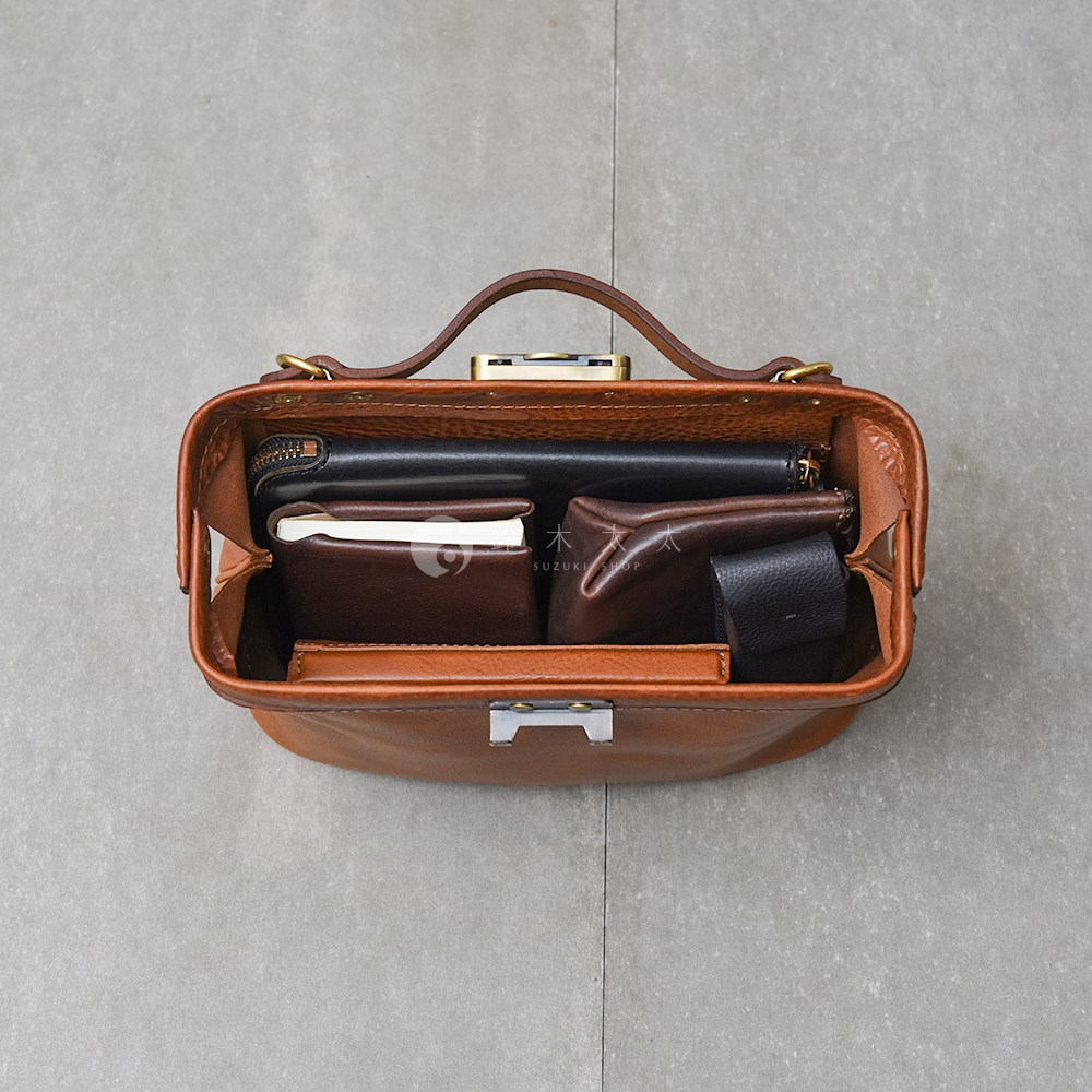 HERZ 職人手作皮革 Organ 鎖孔式大開口肩背包 M-7 內部，包含黑色長夾、咖啡色短夾、筆記本以及一個黑色小零錢包。