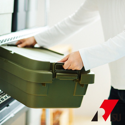 綠色塑膠收納箱，有兩個提把和卡扣，一個人正將箱子從架子上取出。