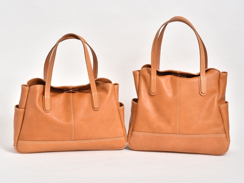 兩款棕褐色皮革橫式肩背托特包，包身縫線清晰，兩側有側袋，款式簡約。