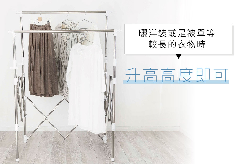 雙桿不鏽鋼曬衣架，架身由銀色不鏽鋼製成，兩側有白色塑膠零件。衣架上懸掛著三件衣物：一件深棕色長裙、一件條紋襯衫和一件白色連衣裙。