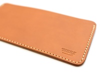 職人手作皮革紙鈔收納夾，淺棕色牛皮材質，車縫線清晰，右下角壓印「HERZ MADE IN JAPAN」字樣。