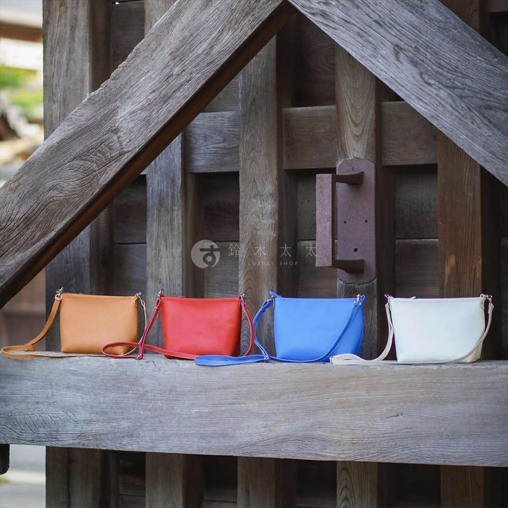 四款京都職人手作隨身側背包，分別為橘色、紅色、藍色與白色。包款皆為皮革材質，設計簡約，可斜背。