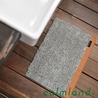 Ward Robe S 尺寸的灰色玄關地墊，材質為絨毛，觸感柔軟，背面有防滑設計，可放置於木質地板上，靠近一個白色陶瓷盆。