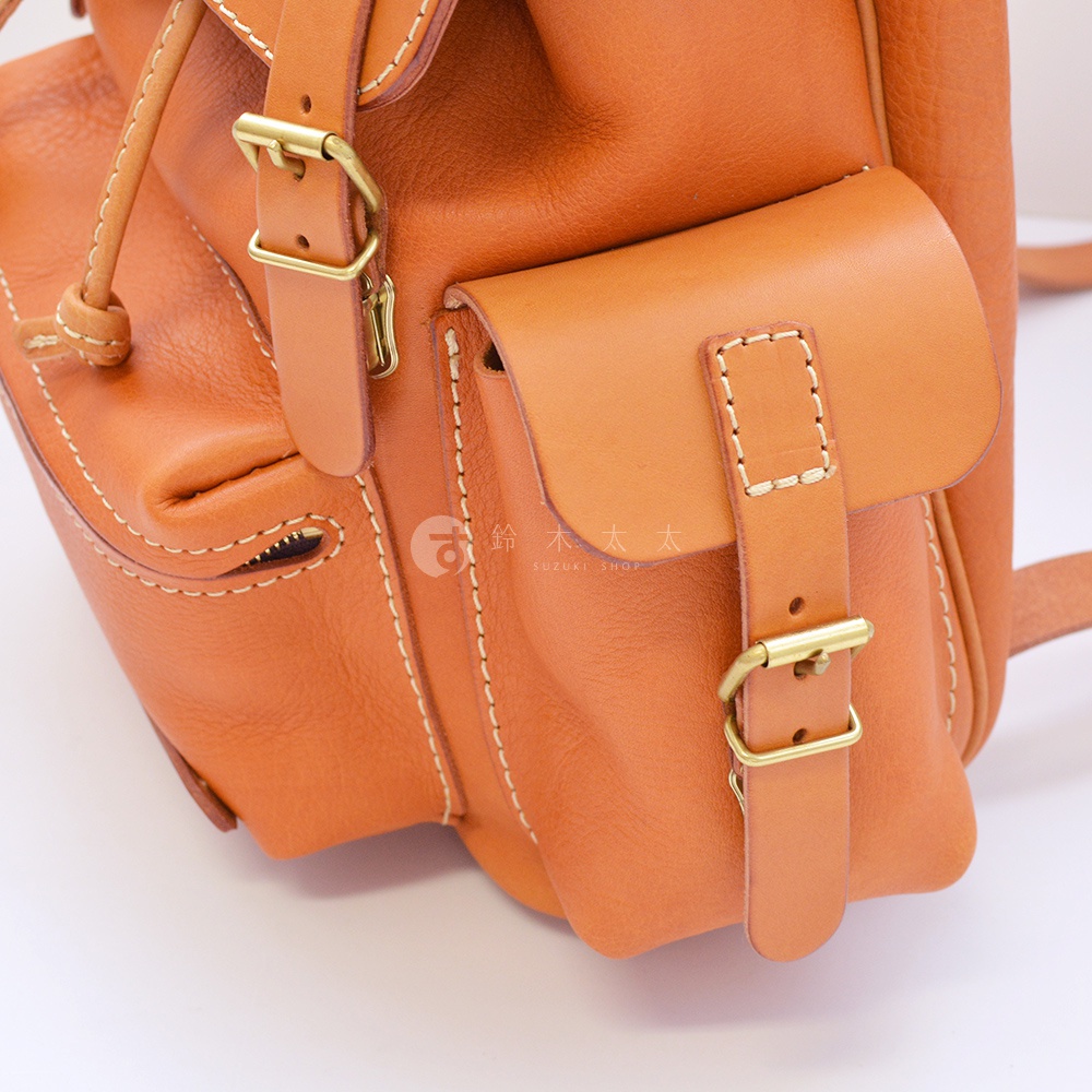 職人手作皮革復古風旅行後背包，採用棕色皮革材質，搭配金色金屬扣環與白色縫線，外觀有翻蓋式前袋及可調節式肩帶。