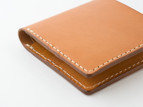 職人手作皮革二折短夾，淺棕色，縫線清晰，材質光滑，簡約設計。