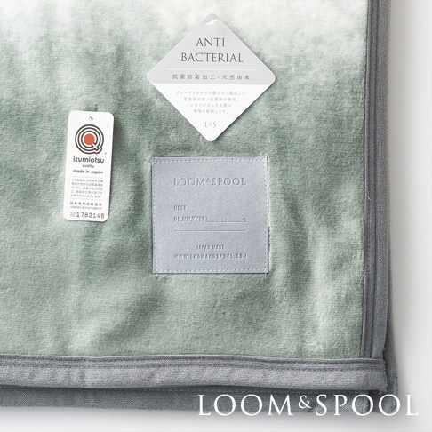 淺綠色短絨雙人毯，材質舒柔，帶有「ANTI BACTERIAL」標籤，顯示抗菌防臭天然由來，以及「LOOM & SPOOL」品牌標誌和日本製造資訊。
