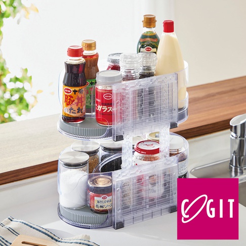 透明塑膠材質的雙層橢圓旋轉調味收納盤，盤上擺放著各種醬料瓶、調味料罐，如醬油、沙拉醬、果醬、糖罐等，收納盤下方有灰色的旋轉底座。