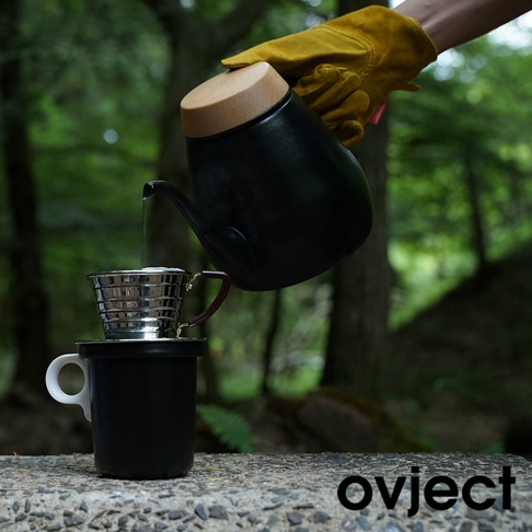 黑色琺瑯馬克杯，搭配白色杯耳，上方放置銀色金屬濾杯，正在進行手沖咖啡。