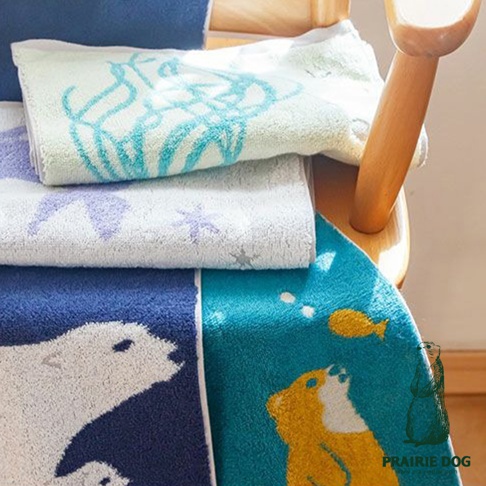 Zootto 今治動物刺繡雙色運動毛巾，疊放展示。最上方為淺綠色毛巾，飾有藍色線條圖案。中間為白色毛巾，繡有紫色星星與動物輪廓。下方為深藍色毛巾，印有白色北極熊圖案，右側為藍綠色毛巾，印有黃色小熊與魚的圖案。