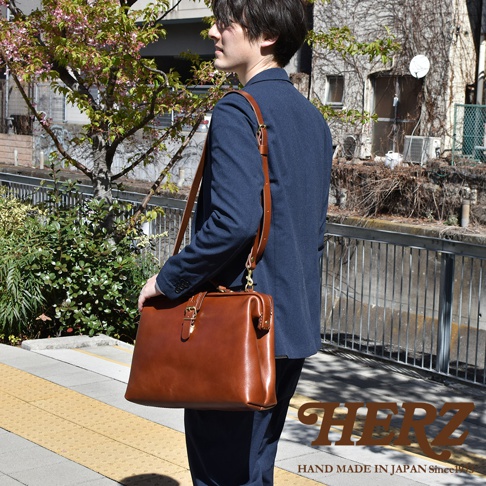 職人手作皮革軟式杜勒斯包，採用光滑棕色皮革製成，配有金色金屬扣環和可拆卸肩帶，展現經典的醫生包造型。