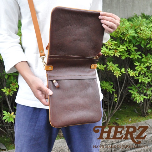 職人手作雙色直式斜背包，深棕色皮革包身搭配淺棕色翻蓋與背帶，質感純牛皮。