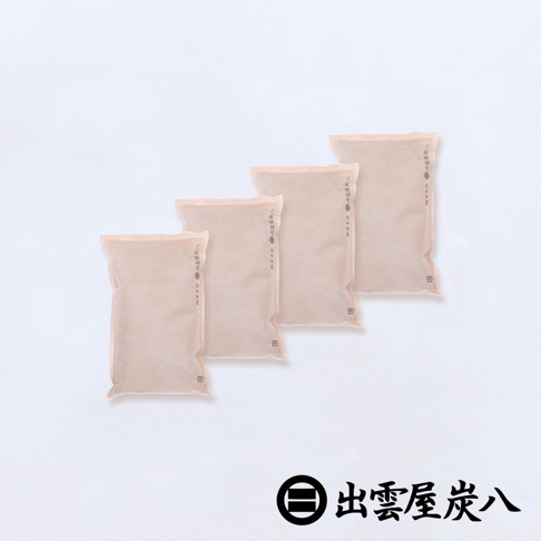 四件淺米色、扁平的調濕木炭包，表面有細密的網格紋路和印製的文字，堆疊擺放於白色背景上。