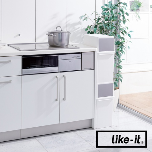 白色長版可疊垃圾桶，前開式設計，具有灰色抽屜面板，放置於廚房角落，旁邊有綠色植物。