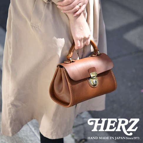 棕色皮革迷你手提包，有金色金屬鎖扣和提把，展現職人手作質感。