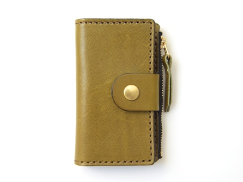 黃褐色皮革製作的零錢鑰匙包，附有金色壓扣和黑色拉鍊，右側有皮革拉鍊頭，邊緣有縫線。