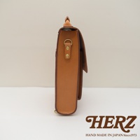 皮革復古後背包，側邊視角，呈現原色皮革材質，配有金色 D 形環和鉚釘。