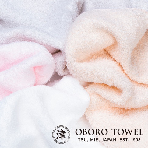 柔軟的毛巾堆疊，呈現粉色、白色和淡橘色。毛巾材質蓬鬆，紋理清晰可見。