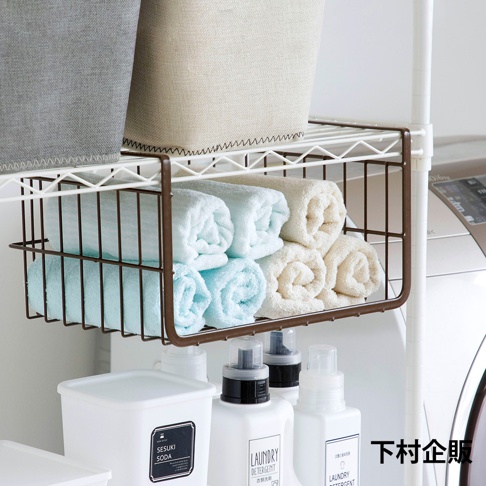 深棕色金屬網籃掛在白色層架上，籃內整齊擺放著捲起來的淺藍色和米白色毛巾。