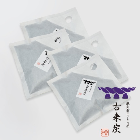 四件方形白色透氣包裝的調濕木炭，內部為深灰色炭粒，包裝上有日文標籤和提孔，其中一件包裝上可見紫色繩結圖案。