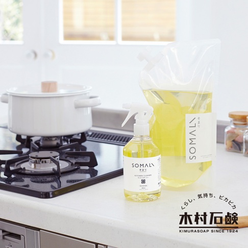 SOMALI 泡沫式廚房清潔劑，透明噴瓶裝有黃色液體，附白色噴頭。旁邊為同品牌 300ml 補充包，裝有黃色清潔劑。背景為白色廚房檯面，爐上放有白色鍋子。