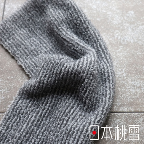 圖片中的文字是「日本桃雪」。這張圖片展示了一條柔軟的灰色毛巾，上面有明顯的紋理。