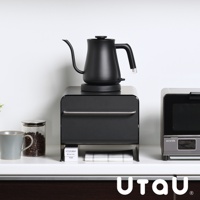 黑色抽屜式多功能萬用收納整理櫃，上方擺放黑色細長嘴咖啡壺，櫃子前方有銀色拉柄。左側有灰色馬克杯和裝有咖啡豆的玻璃罐，右側有小型銀色烤箱。