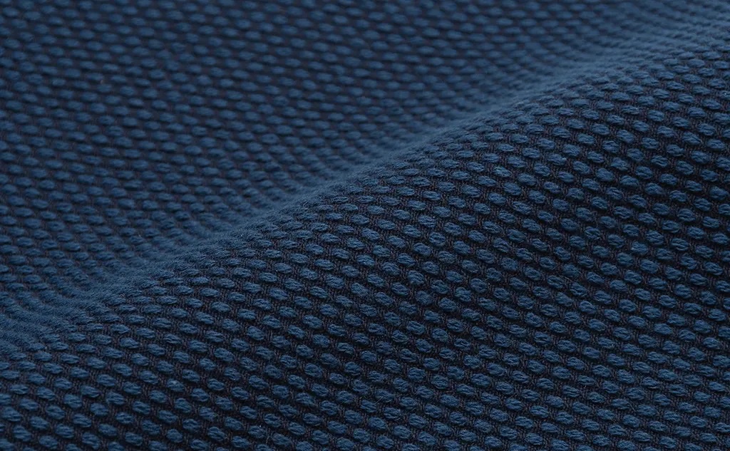 深藍色刺子織紋理，帶有細小的凸起點狀圖案，布料略有彎曲，呈現柔軟的質感。