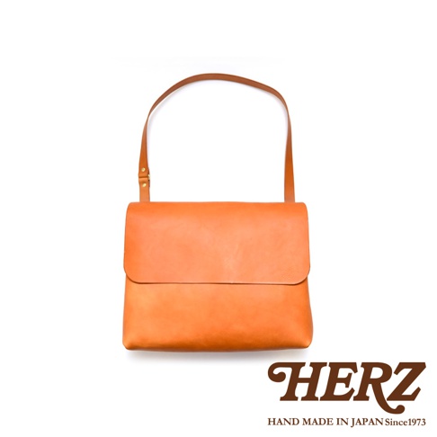 橙色皮革製成的經典郵差包，附有同色系的肩帶，包款設計簡潔，適合日常攜帶。