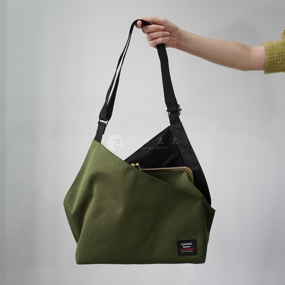 由京都職人手工製作的 AYANOKOJI Sarei 機能布方形口金單肩包，綠色包身搭配黑色內裡，由手提著，包上可見品牌標籤。