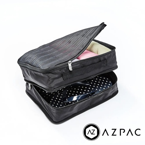 AZPAC 黑色分層擴充旅行收納袋組，上方網狀袋開口露出粉色和米色衣物，下方袋子內有黑色圓點圖案的物品。